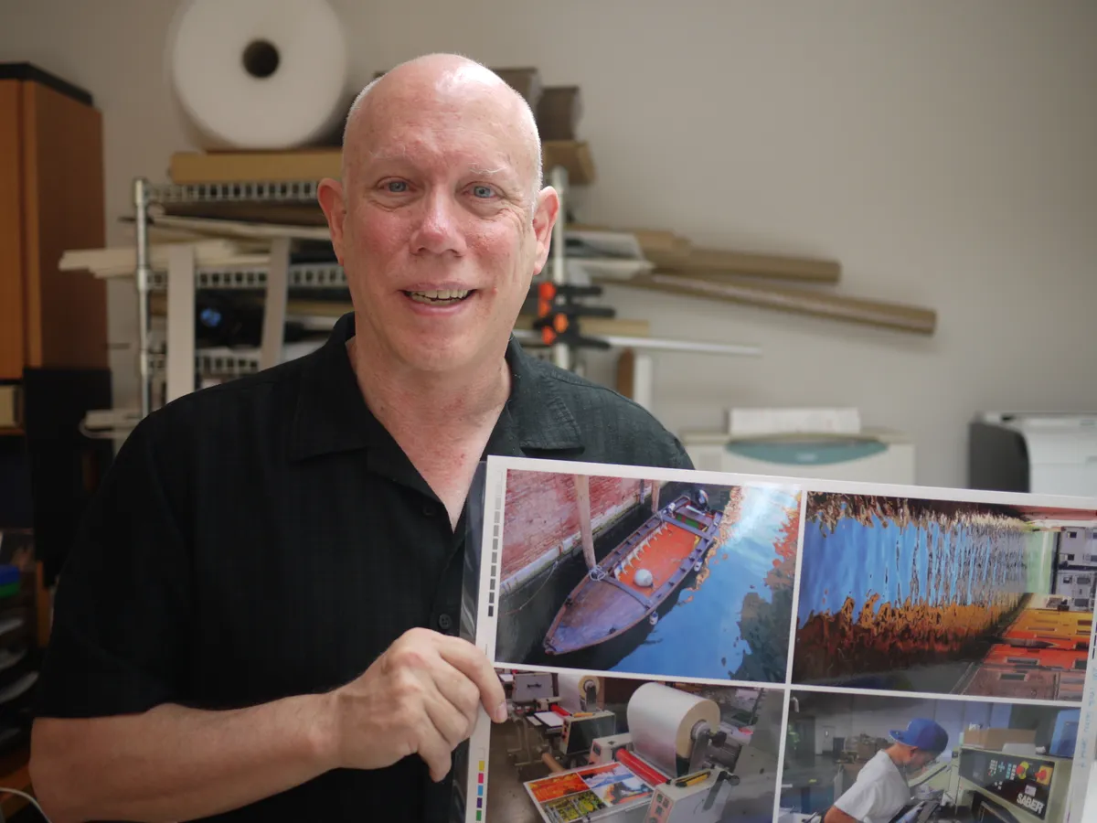 Bill Atkinson holding a sheet of photographic prints in his studio.